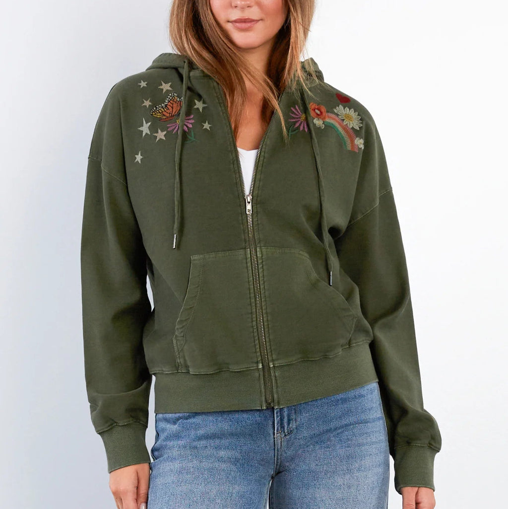 Woman wearing an olive green hoodie with floral embroidery on a white background